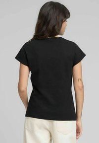 Maglietta nera in cotone con maniche corte, scollo rotondo e taglio dritto. Presenta dettagli di cuciture sottili e una vestibilità rilassata.