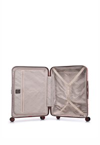 Valise rigide couleur bordeaux avec une surface texturée, ouverte pour révéler un intérieur crème équipé de sangles et d'un compartiment zippé.