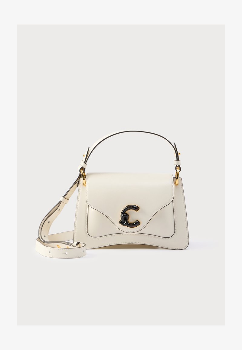 Crèmekleurige leren handtas met een gebogen ontwerp, zwart logo-accent en gouden beslag. Inclusief een afneembare riem. Glad oppervlak.