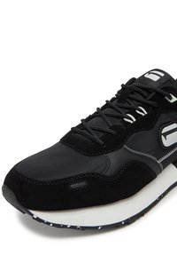 Melni sporta apavi ar kombinētu ādas un zamšādas augšdaļu, ar šņorēm, baltu vidējo zolīti un melnu pēdas zolīti ar pintiņu rakstu.