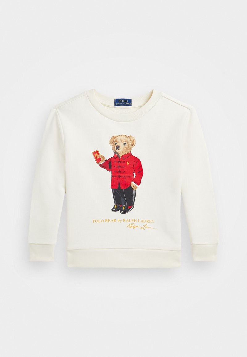 Sweatshirt couleur crème avec une illustration d'un ours portant une veste rouge tenant une carte. Marque "Polo Bear" en orange sous l'image.