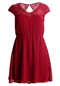 Vestido rojo con mangas de capucha, cuerpo de encaje, escote en forma de V, cintura elástica y una falda fluida. Presenta un corte en forma de llave en la parte posterior.
