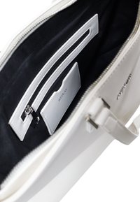 Weiße Handtasche mit strukturiertem Äußeren; das Innere verfügt über ein schwarzes Futter, eine Reißverschlusstasche und ein Kartenfach mit der Aufschrift "REPLAY". Silberfarbene Hardware-Akzente.