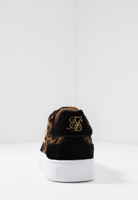 Baskets en suede noires et imprimé léopard avec une semelle en caoutchouc blanche et un logo doré brodé sur le talon. Design simple et bas profil.