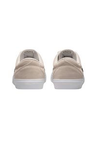 Zapatillas de ante beige de diseño de perfil bajo, con suelas de goma blanca y sutiles acentos en negro, que cuentan con un collar y una pestaña en el talón acolchados.
