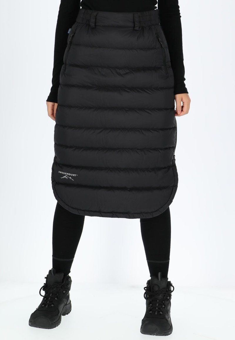 Black puffy skirt with quilted design, elastic waistband, and side pockets, worn over black leggings and sturdy black boots.
