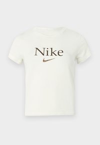 Biele krátke tričko s krátkym rukávom s hnedým nápisom "Nike" a logom swoosh Nike s leopardím vzorom na hrudi.