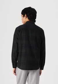 Black and green plaid button-up shirt with long sleeves and a classic collar, made of soft fabric with a comfortable fit, shown from the back.