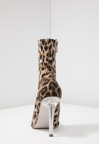 Botte chevillère en imprimé léopard avec un élégant talon aiguille, fabriquée en matériau doux. Dotée d'une fermeture éclair et d'un accent de talon transparent.