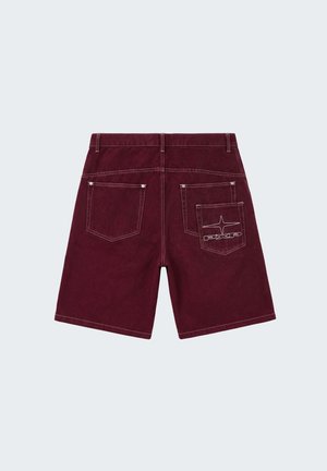 Short en jean marron avec deux poches arrière, une poche ornée d'une étoile brodée blanche et du logo "PXG". Passants de ceinture visibles et coutures contrastantes.