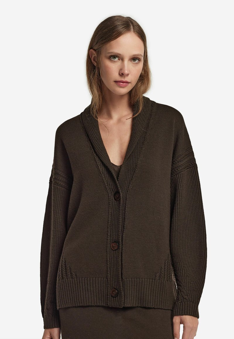 Brun stickad cardigan med sjalkrage, oversized passform och sju stora knappar. Har texturerad ribbing och mjuk tyger.