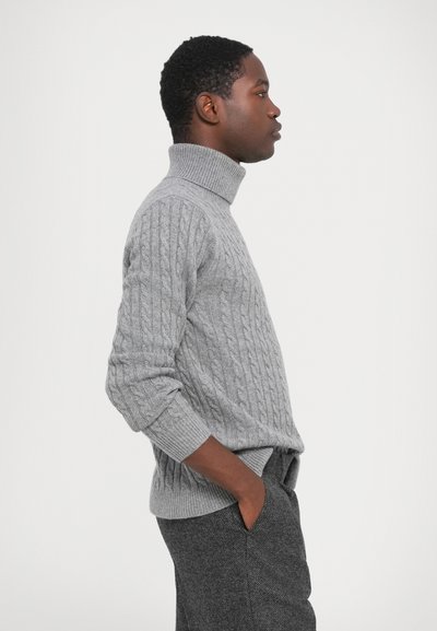 Grå kabelstrikket turtleneck sweater med ribbede manchetter og hals. Blød tekstur og afslappet pasform. Bæres med mørkegrå bukser.
