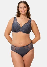 Szary koronkowy biustonosz i pasujące majtki. Biustonosz ma ząbkowane koronkowe krawędzie, szerokie ramiączka i ozdobne przeszycia. Majtki zdobią koronkowe akcenty.