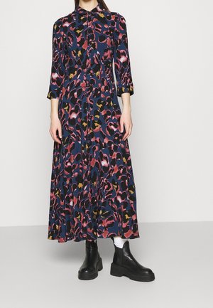 Lang navy kjole med et multicolor abstrakt leopardprint, knapfront og trekvartærmer. Sammen med sorte ankelstøvler.