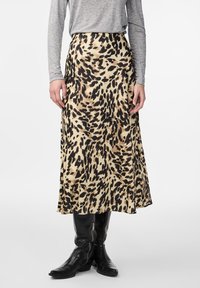 Leopardmønstret A-linje midi skjørt laget av glatt, lett stoff. Har høy midje og flytende design. Bæres med svarte knelange støvler.