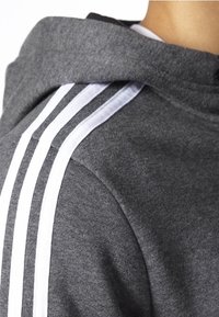 Sudadera gris con un acabado texturizado, que presenta acentos de rayas blancas en las mangas y un diseño clásico de capucha.