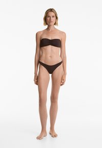 Rjav bandeau bikini z nabranimi detajli na vrhu in ujemajočimi se nizkimi hlačkami, izdelan iz gladkega, elastičnega materiala. Enostaven dizajn, minimalni detajli.