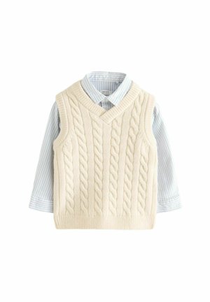 Gilet en tricot crème à torsades avec un col en V, superposé à une chemise à col rayée bleu clair et blanche avec des poignets à boutons.