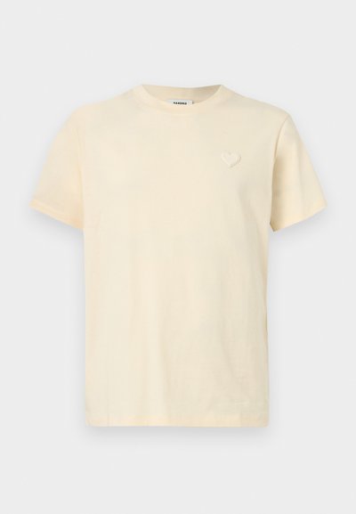 Κοντομάνικη μπλούζα χρώματος κρέμα με στρογγυλή λαιμόκοψη και μικρό κεντητό καρδιά στο αριστερό μέρος του στήθους.