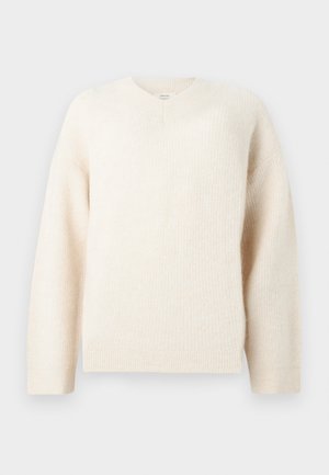 Kermanvärinen neulepaita, jossa on pitkät hihat, joustavat hihansuut ja helma sekä V-muotoinen neulekoristelu pääntiessä.
