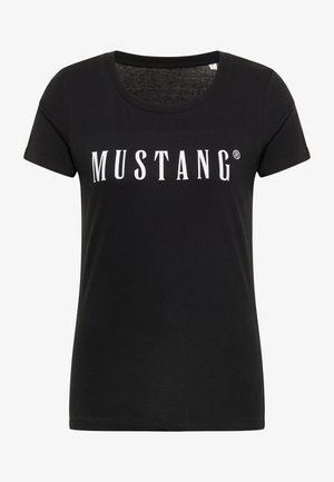 Mujer vistiendo una camiseta sencilla negra de manga corta y jeans azules de mezclilla, mostrada de espaldas sobre un fondo blanco.