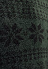 Green knitted fabric featuring a black floral pattern with geometric accents, displaying a textured surface and consistent design.