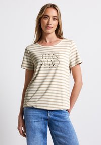 T-shirt rayé beige clair en tissu doux, avec des manches courtes et un col rond. Texte graphique imprimé sur le devant.