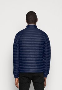 Granatowa kurtka puchowa z poziomym pikowaniem. Posiada stójkę, elastyczne mankiety oraz gładkie, błyszczące wykończenie.