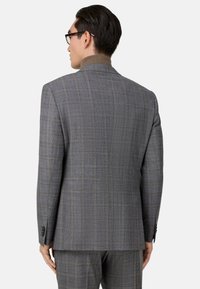 Blazer de cuadros gris con un diseño estructurado y un cuello marrón en contraste. Presenta un tejido suave y puños abotonados.