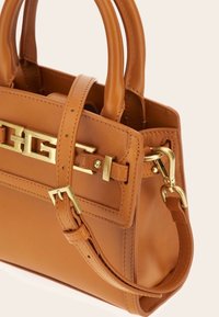 Sac à main en cuir tan avec boucle dorée, bandoulière réglable, doubles poignées arrondies et couture détaillée.