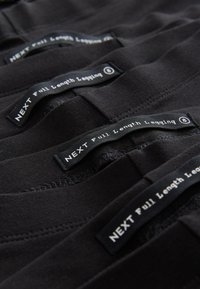 Sorte leggings i fuld længde arrangeret i lag, med mærkater "NEXT Full Length Legging" i hvid tekst. Blødt stof med en glat tekstur.