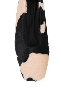 Czarno-beżowe baleriny w wzór skóry krowy, z puszystą fakturą i zaokrąglonym czubkiem. Wnętrze jest czarne, bez widocznych elementów metalowych.