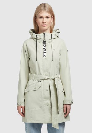 Veste de pluie vert clair avec capuche, fermeture éclair, taille ceinturée et grandes poches frontales. Comprend un détail de logo et un tissu durable.
