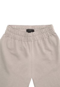 Jasnoszare dresy z elastycznym pasem. Charakteryzują się gładką, miękką fakturą oraz metką wskazującą rozmiar M/L. Minimalistyczny design.