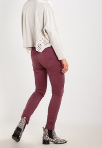 Světle šedý pletený crop svetr s krajkovým lemem, zkombinovaný s bordó skinny džíny a černobílými leopardími kotníkovými botami.