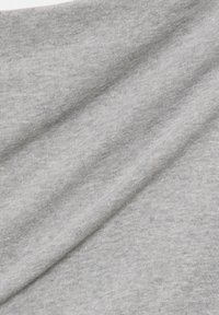 Hellgrauer Stoff mit einer glatten, weichen Textur, die subtile Farb- und Webmuster-Variationen aufweist und sanft in Falten fällt.