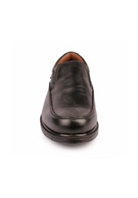 Zapato de cuero negro sin cordones, con puntera redonda, textura suave y un sutil detalle de costura alrededor del borde. La suela es plana y resistente.