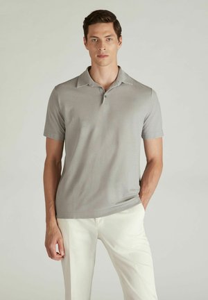 Polo de color gris claro con una tapeta de botones, mangas cortas y una textura suave, combinado con pantalones blancos. Diseño sencillo sin estampados.