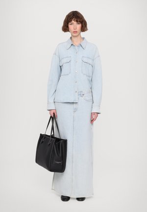 Light blue denim jacket with long sleeves, button front, and two chest pockets, paired with a matching long denim skirt and a black tote bag.