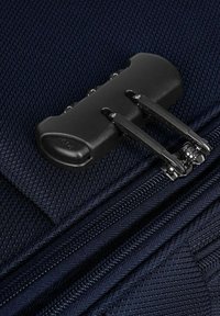 Valigia in tessuto blu navy in primo piano, con una cerniera nera a doppio cursore, superficie testurizzata e cuciture rinforzate.