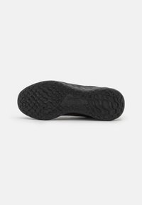 Sole di scarpa da corsa nera con gomma testurizzata per trazione, caratterizzata da un motivo ondulato e scanalature per aderenza, etichettata con "Nike Running."