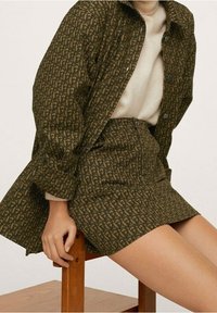 Ensemble chemise et jupe à motifs marron en tissu texturé, avec une fermeture à boutons sur la chemise et une coupe cintrée sur la jupe.