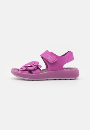 Sandalia rosa para niños con tira ajustable y flor decorativa en la parte superior, suela acolchonada para mayor comodidad, vista lateral.