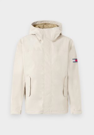 Beige hoodie met voorzakken en klep-sluitingen, lange mouwen en een klein rechthoekig logo-opdruk op de bovenste linker mouw.