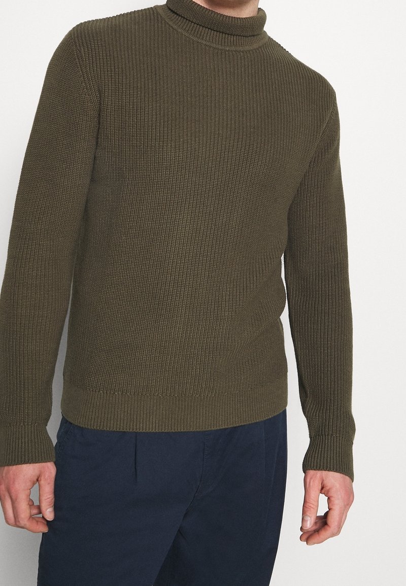 Olivgrön, ribbad turtleneck-tröja med en figursydd design och strukturerad stickning. Långa ärmar, enfärgad och rak nederkant.