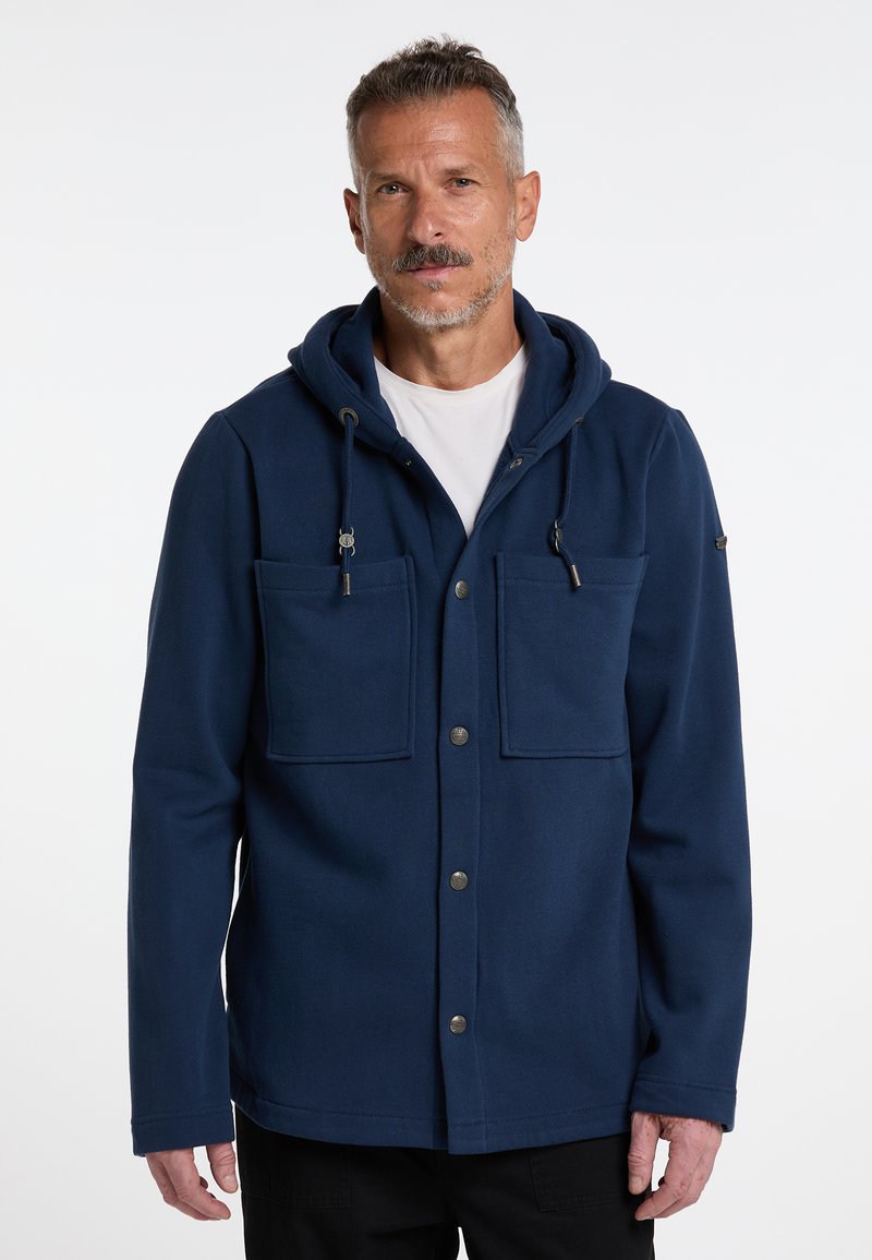Veste à capuche bleu marine en tissu texturé, dotée de deux poches avant, d'une fermeture à bouton et de cordons de serrage réglables sur la capuche.