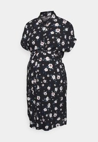 Vestido floral preto feito de tecido leve. Apresenta mangas curtas dobradas, colarinho com botões, faixa na cintura e padrão floral branco com acentos verdes.