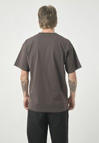 Brown cotton t-shirt with short sleeves and a relaxed fit. Features a crew neck and a smooth texture. No visible logos or patterns.