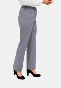 Grijze, op maat gemaakte broek met een elastische tailleband, een zijzak en een rechte pijp. Draagt met zwarte hoge hakken.