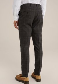 Pantalon gris à carreaux avec une coupe ajustée, doté de deux poches arrière avec des boutons. Fabriqué en tissu texturé, associé à des chaussures marron.